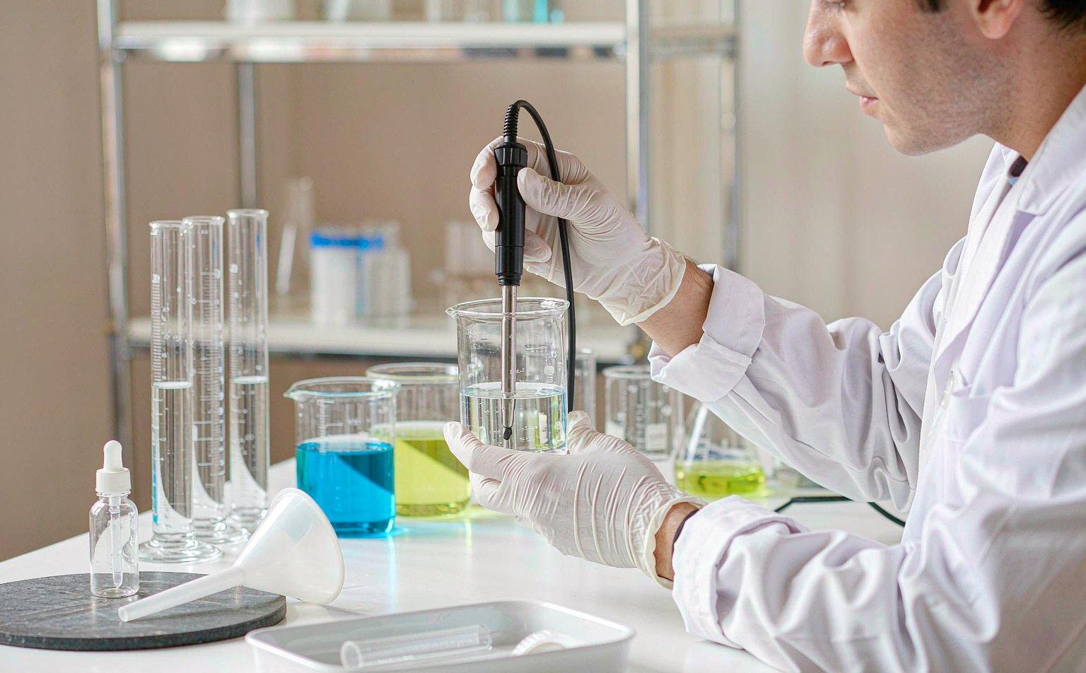 Cosmetic chemist testing serum pH with a meter in a formulation laboratory